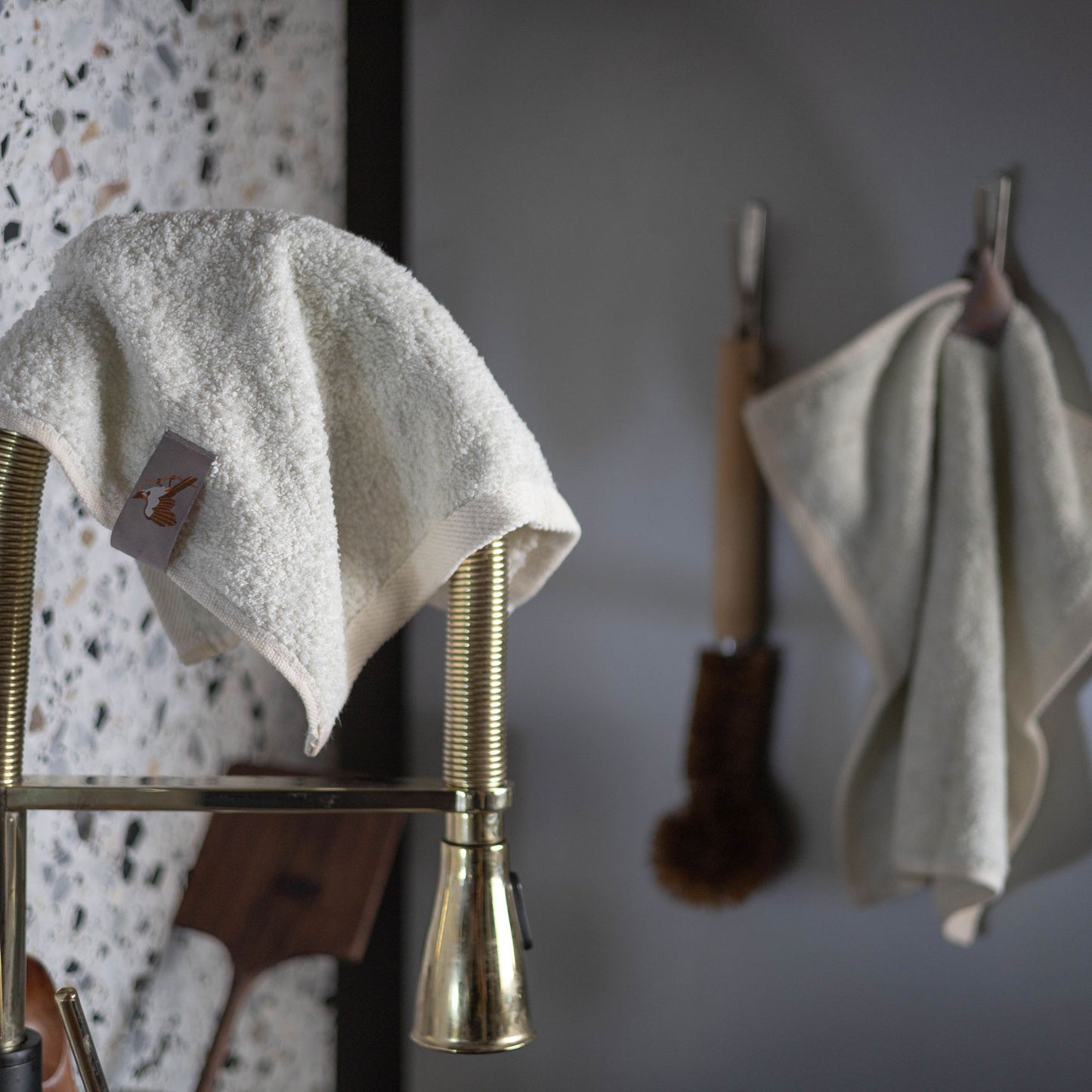 Bulbul Self-sanitizing Premium Copper Face Towel hanging on a brass kitchen faucet, showcasing its antibacterial and odour-resistant fabric.